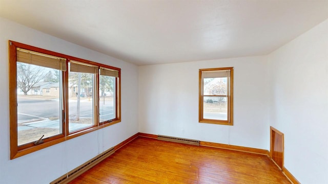 spare room featuring a healthy amount of sunlight, light wood-style flooring, and a baseboard radiator