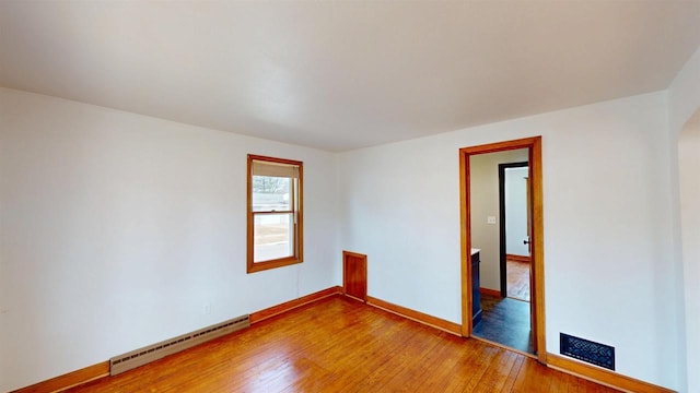 empty room with baseboards, baseboard heating, and light wood finished floors