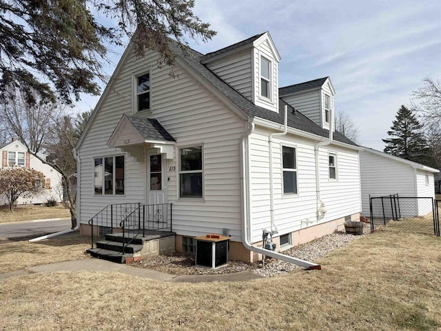 exterior space with a yard, fence, and a shingled roof