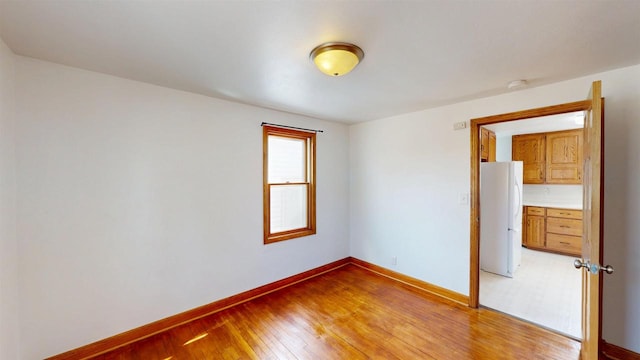 unfurnished room featuring baseboards and light wood-style floors