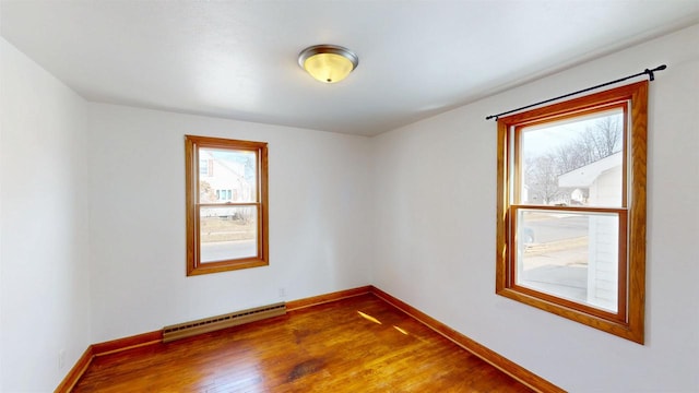 spare room with wood finished floors, baseboards, and a baseboard radiator