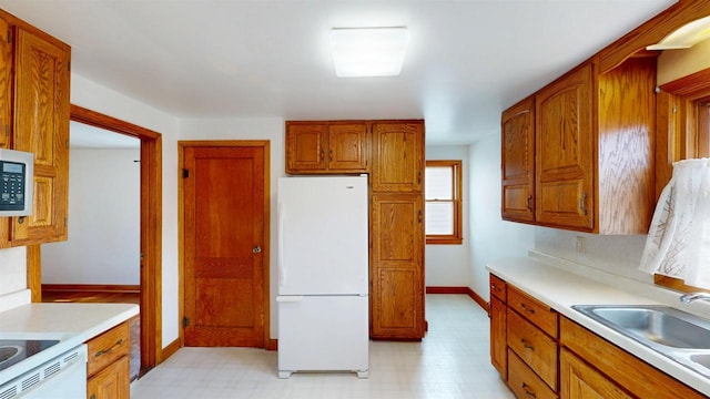 kitchen with light floors, light countertops, freestanding refrigerator, and a sink