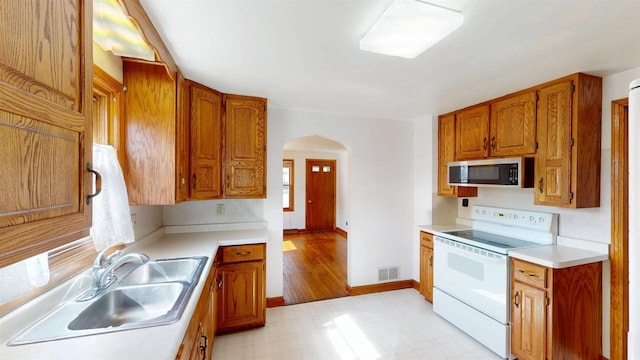 kitchen with white electric range oven, visible vents, arched walkways, a sink, and stainless steel microwave