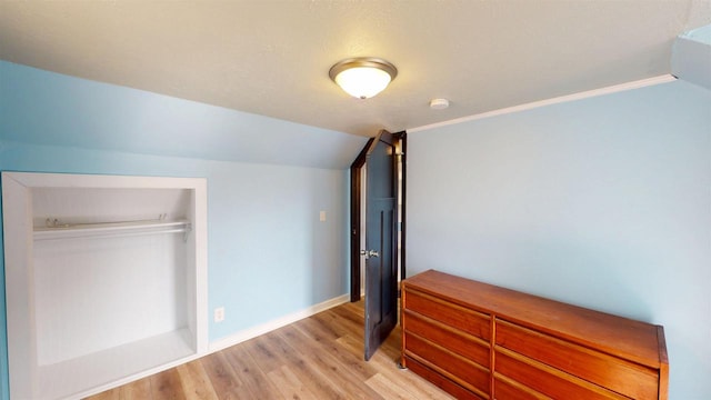 bedroom featuring baseboards, lofted ceiling, and light wood-style floors