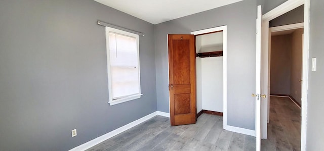 unfurnished bedroom featuring a closet, baseboards, and wood finished floors