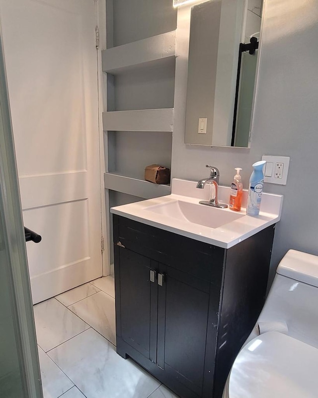 half bath with vanity, toilet, and marble finish floor