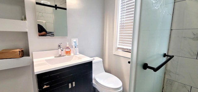 bathroom with toilet, a shower stall, and vanity