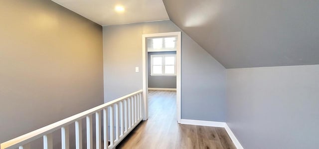 hall featuring vaulted ceiling, baseboards, and wood finished floors