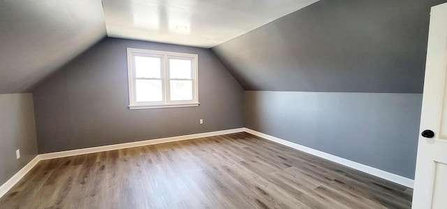 additional living space with baseboards, lofted ceiling, and wood finished floors