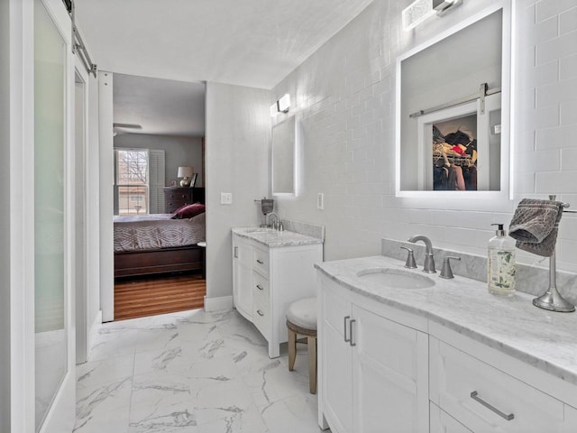 full bath with two vanities, marble finish floor, ensuite bathroom, and a sink