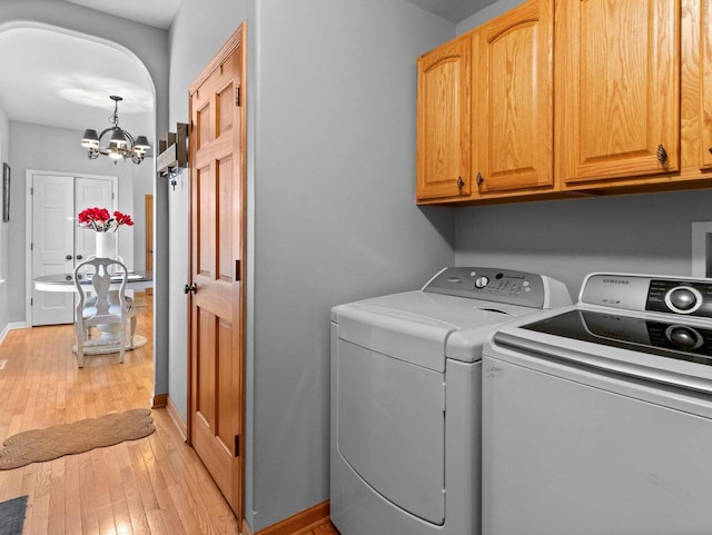 laundry area featuring baseboards, washer and dryer, light wood-style floors, a notable chandelier, and cabinet space