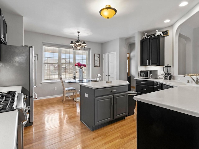 kitchen with light wood-style flooring, arched walkways, appliances with stainless steel finishes, and a sink