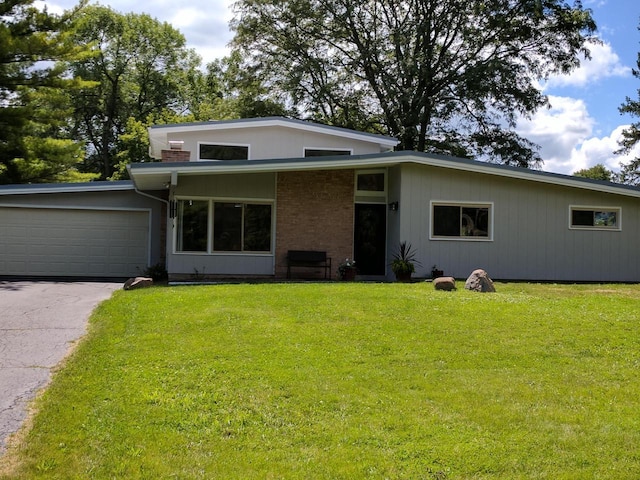 3103 W Riverland Dr, Mequon, WI 53092 - view of front facade featuring driveway, a garage, and a front lawn
