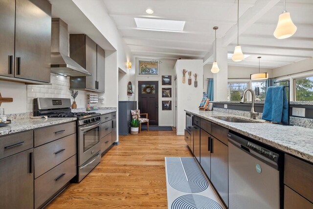 3103 W Riverland Dr, Mequon, WI 53092 - kitchen featuring a sink, light wood finished floors, dark brown cabinets, appliances with stainless steel finishes, and wall chimney exhaust hood