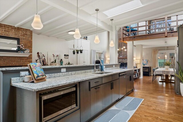 3103 W Riverland Dr, Mequon, WI 53092 - kitchen with beam ceiling, a sink, appliances with stainless steel finishes, light wood-type flooring, and decorative light fixtures