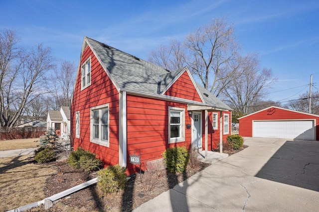 view of front of house featuring a garage, an outbuilding, and roof with shingles