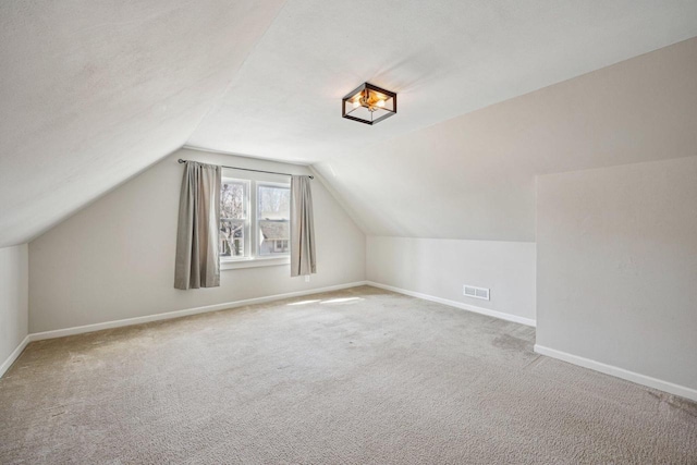 bonus room featuring baseboards, lofted ceiling, carpet, and visible vents