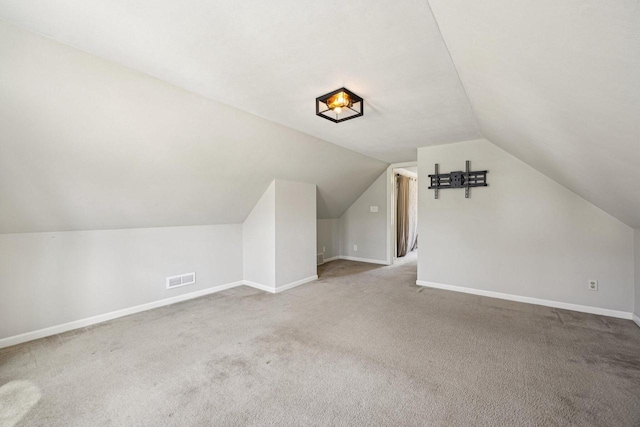 additional living space featuring carpet, vaulted ceiling, baseboards, and visible vents