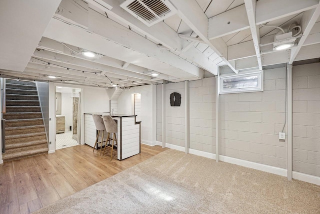 below grade area featuring visible vents, stairway, baseboards, and wood finished floors