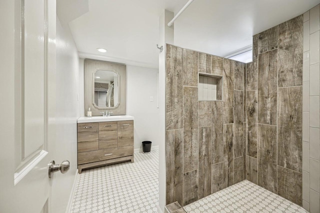 full bath featuring recessed lighting, tiled shower, vanity, and baseboards