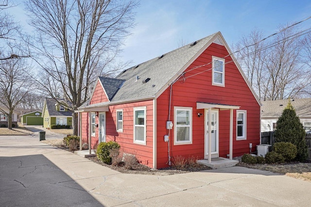 bungalow-style home featuring central AC unit, a shingled roof, and fence