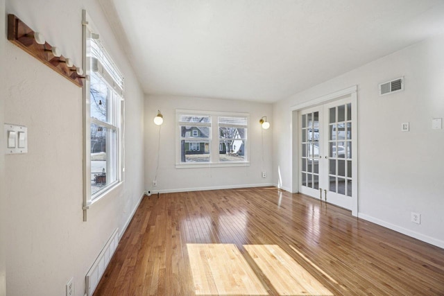 unfurnished room featuring visible vents, french doors, baseboards, and wood-type flooring