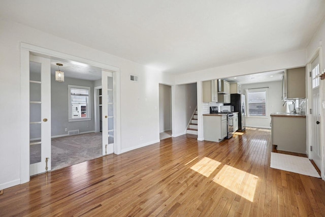 unfurnished living room featuring visible vents, baseboards, and hardwood / wood-style flooring