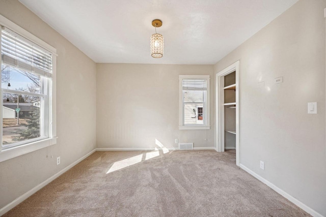 carpeted spare room featuring visible vents, baseboards, and a chandelier