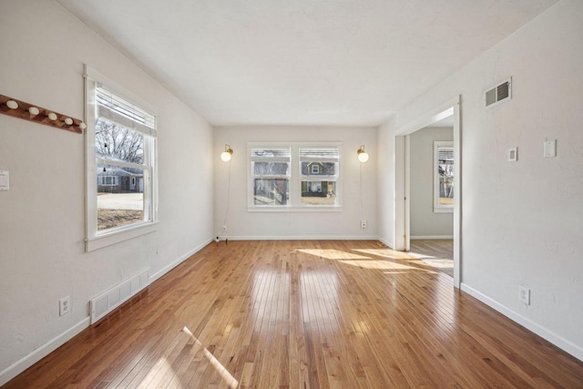 unfurnished room with visible vents, baseboards, and wood-type flooring