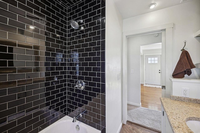 full bathroom with baseboards, vanity, wood finished floors, and shower / bathtub combination