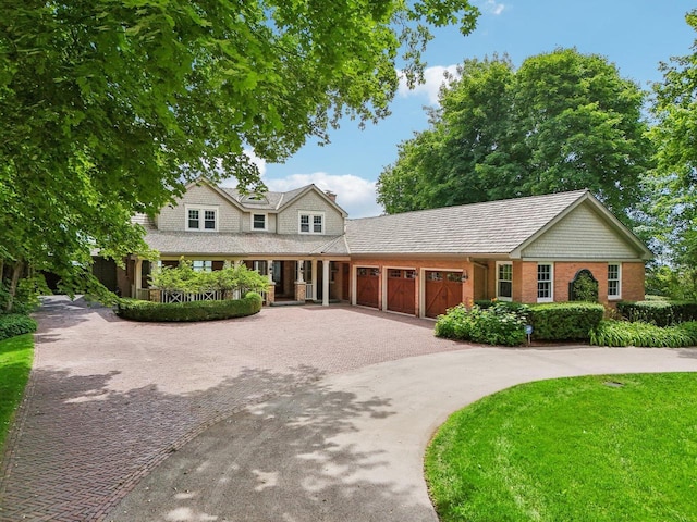 view of front of home with a garage, curved driveway, and a front lawn