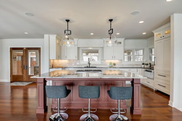 kitchen featuring glass insert cabinets, light stone countertops, dark wood-type flooring, and white cabinetry