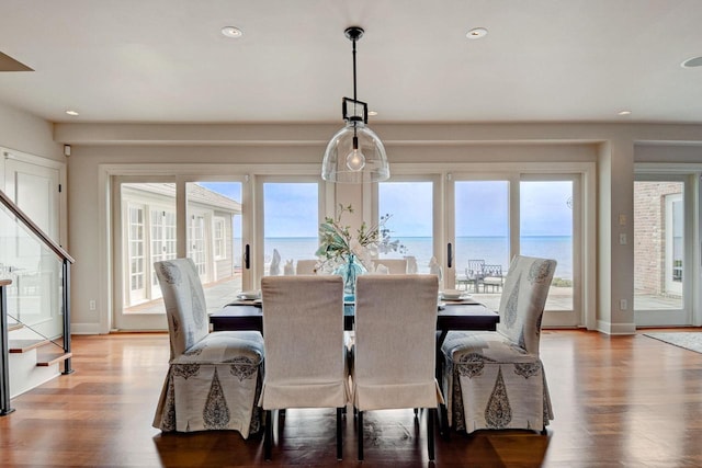 dining room with a wealth of natural light, stairway, and wood finished floors