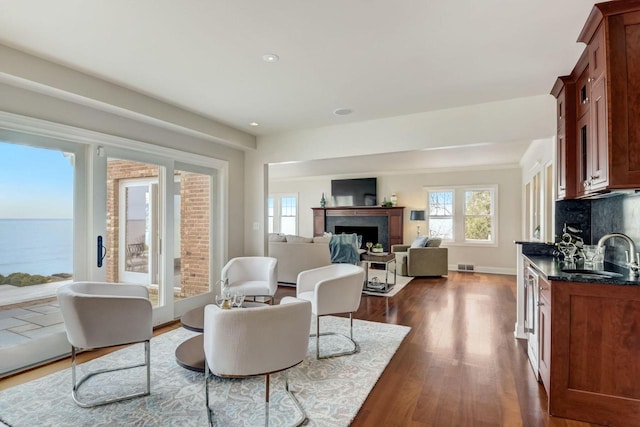 sitting room featuring visible vents, a healthy amount of sunlight, a fireplace, and dark wood-type flooring