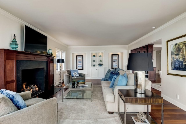 living area with a fireplace, crown molding, baseboards, and wood finished floors