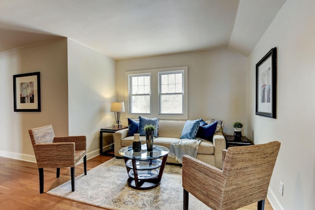 living room featuring lofted ceiling, wood finished floors, and baseboards