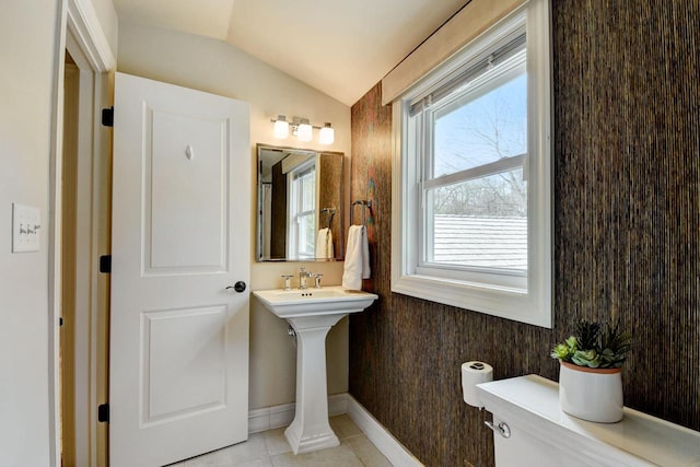 half bathroom featuring tile patterned flooring, toilet, baseboards, and lofted ceiling