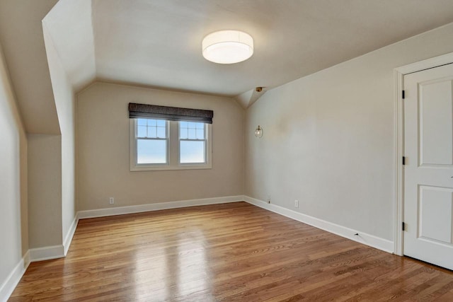 interior space with baseboards, lofted ceiling, and wood finished floors