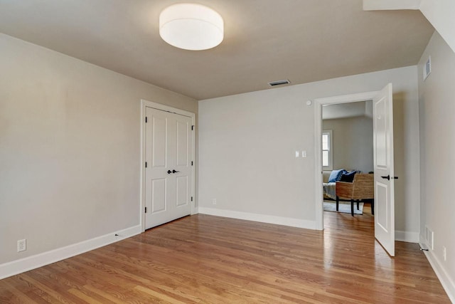 unfurnished room with baseboards, visible vents, and light wood-type flooring