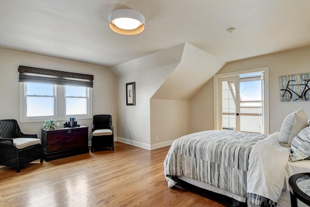 bedroom featuring lofted ceiling, light wood-style flooring, and baseboards