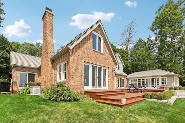 rear view of property with brick siding, a lawn, french doors, a chimney, and a deck