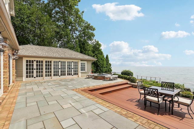 view of patio with outdoor dining area, a water view, and a fire pit