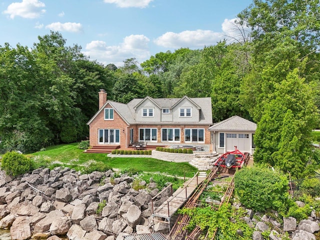 view of front of house with entry steps, an outdoor structure, a front yard, brick siding, and a chimney