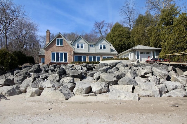 view of front facade with an outbuilding, a detached garage, and a chimney