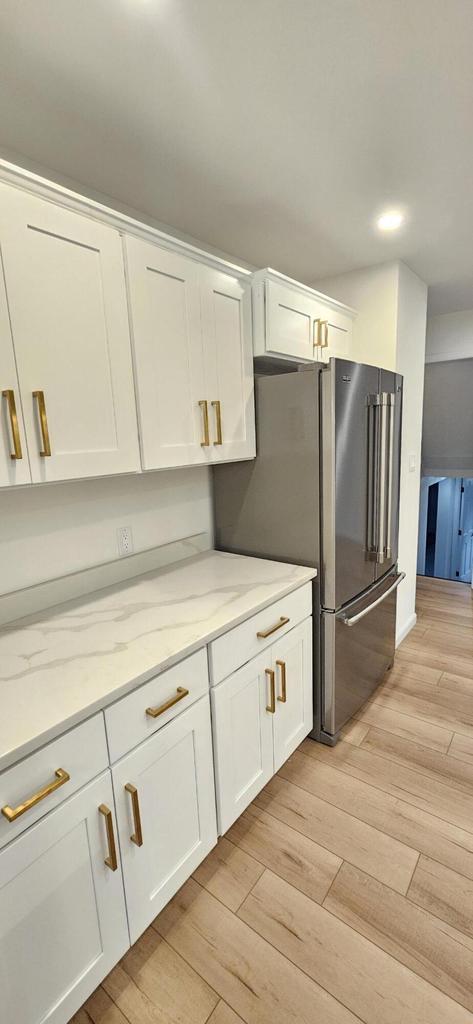 kitchen with white cabinetry, light wood-style floors, and freestanding refrigerator