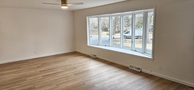 unfurnished room with baseboards, wood finished floors, visible vents, and ceiling fan