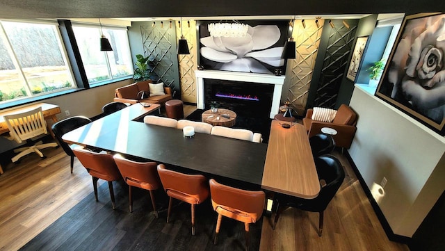 dining space with a glass covered fireplace, wood finished floors, and baseboards