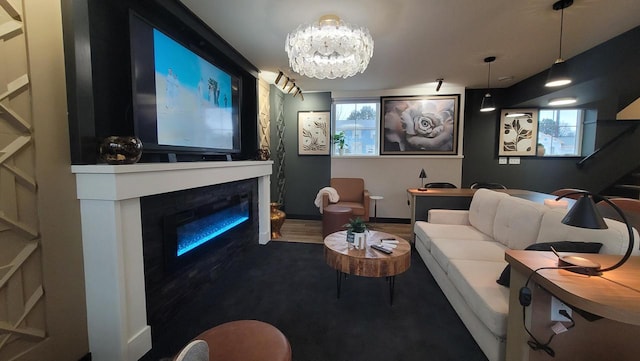 cinema featuring a wealth of natural light, a glass covered fireplace, a chandelier, and wood finished floors