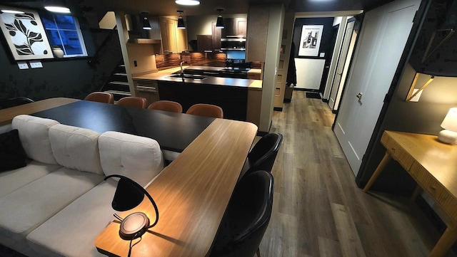 kitchen with backsplash, baseboards, light wood-type flooring, a peninsula, and a sink