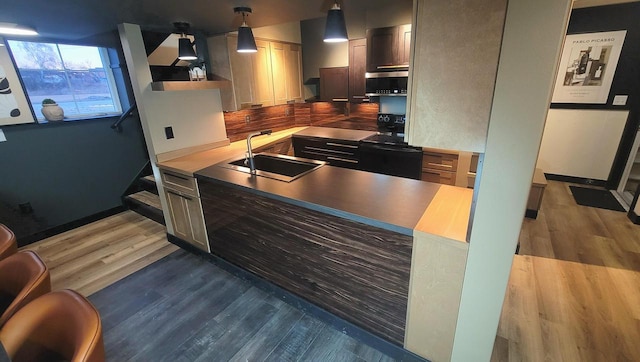 kitchen with extractor fan, a peninsula, wood finished floors, black / electric stove, and a sink